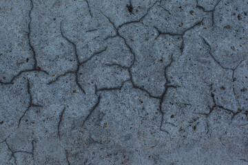 Texture of the dried earth. Dark gray background with cracks and hollows. Drought and lack of moisture in the soil. The consequences of abnormal heat. Environmental disaster. Global warming.