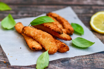 
 Crispy  deep fried   chicken strips and wedges potato. Breaded  with cornflakes chicken  breast fillets  with chilly peppers and fresh   basil on wooden rustic background