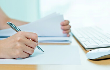 Close up of hand writing and using computer in the office