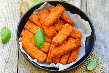 Close up of   Crispy breaded  deep fried fish fingers with breadcrumbs served  with remoulade sauce and  lemon Cod Fish Nuggets on rustic wood table background