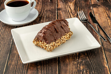 Dessert Cake from Malaga on wooden table. Cake with banana inside, covered with chocolate sauce and hazelnuts.