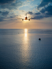 Fototapeta na wymiar Airplane flying over tropical sea atduring sunset,copy space for text.