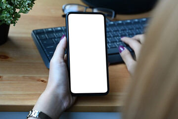 Close up view young woman holding smart phone and typing on wireless keyboard.