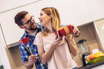 Romantic couple at home. Man giving a present to his girlfriend