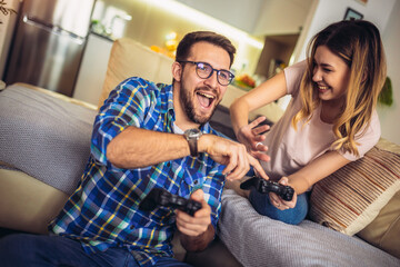 Excited funny couple playing video games at home