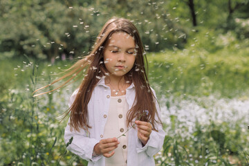 Young girl with long brown and messy hair blowing seeds of dandelion. Child in the countryside