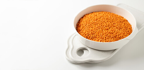 dry orange lentils in a white bowl on a white background, banner, space for text
