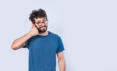 Attractive caucasian young male in casual clothes imitates telephone conversation, keeps hand near ear as if holding mobile phone