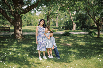 Fototapeta premium Beautiful young mother hugging her little children. Family love and bonding time. Enjoying the nature.