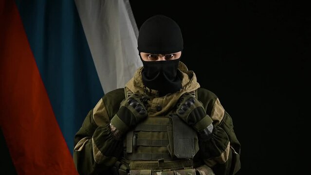 an angry Russian soldier on the background of the Russian flag with a weapon in a balaclava in the role of a terrorist