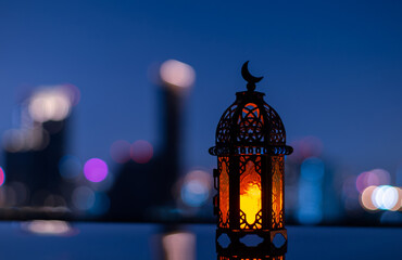 Selective focus of lantern that have moon symbol on top with city background for the Muslim feast...