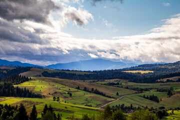 Fototapeta premium hills with forests in the countryside on a summer cloudy day. mountains landscape background.