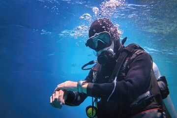 Fully equipped man scuba diver underwater in the blue water - obrazy, fototapety, plakaty