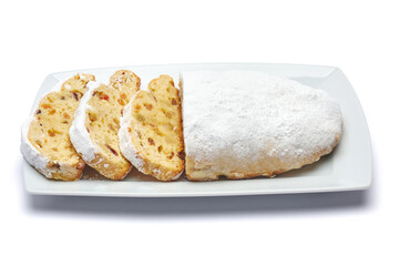 Sliced Traditional Christmas stollen cake with marzipan and dried fruit isolated on ceramic plate