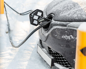 vehicle, power and green energy concept - close up of electric car charging battery in winter