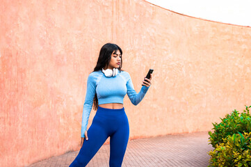 Attractive woman using her mobile phone while playing sports in a park