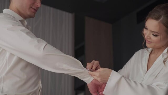 Bride helping groom put on cufflinks