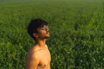 Young indian shirtless boy working in the green fields early in the morning.