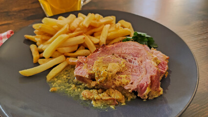 slice of roast pork with mustard on a plate with fries