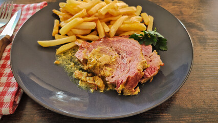 slice of roast pork with mustard on a plate with fries