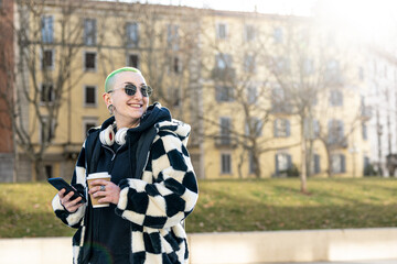 happy yong woman with green hair using smartphone and drinking coffee in a disposable cup,...