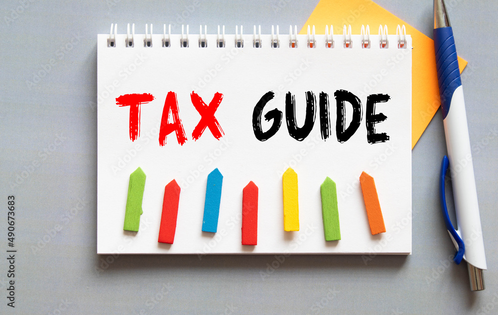 Poster on the table there is a red marker and a white paper tablet on which the text is written - tax guide