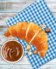 Croissants with chocolate cream and hazelnut on the wooden board.View from above.