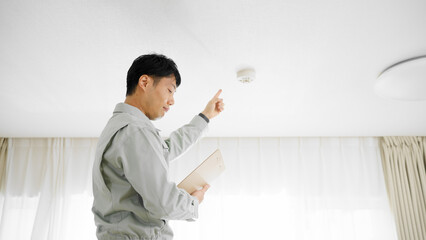 火災報知機の点検をする作業着姿の男性