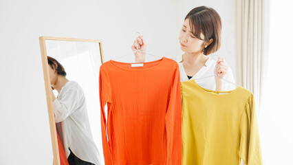 鏡の前で服選びをしている若い女性　ファッションイメージ