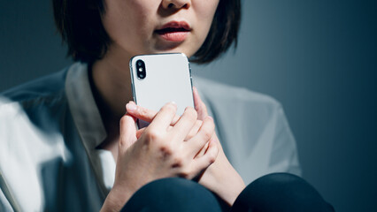 精神障害を患っている若い女性がスマートフォンを使っている