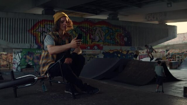 Man having video call on smartphone at skate park. Handsome guy talking online. 