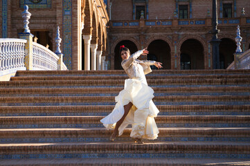 Naklejka premium Flamenco dancer, woman, brunette and beautiful typical spanish dancer is dancing and clapping her hands on the stairs of a square in seville. Flamenco concept of cultural heritage of humanity.