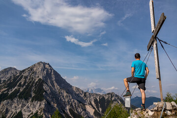 Man admiring the scenic view from summit cross of Ferlacher Spitze on Mittagskogel in the...