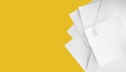 Stacked of white notepad paper sheets on yellow background with copy space.