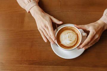A womans hands hold a cup of coffee
