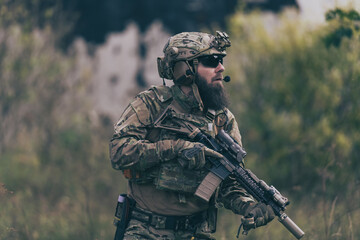 A bearded soldier in uniform of special forces in a dangerous military action in a dangerous enemy area. Selective focus 