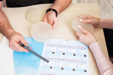 A plastic surgeon doctor shows a sample set of a silicone implants for breast augmentation to a...