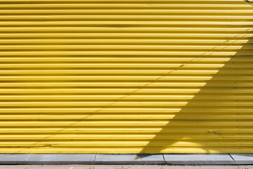 Yellow profiled sheet metal wall with deep shadows on a sunny day