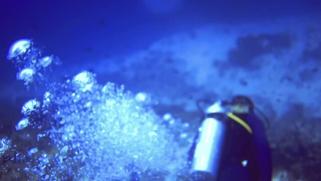 underwater close up view of oxygen bubbles and divers who swim near coral reef