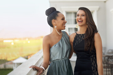 Excitement before the prom. Two young women in evening wear standing on a balcony. © Alexandra/peopleimages.com