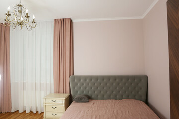 fragment of pink bedroom with curtain, tulle, bed, pillow and nightstand closeup photo