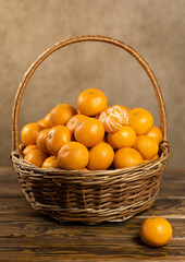 Ripe tangerines in a basket. On a wooden background. Vertical frame.