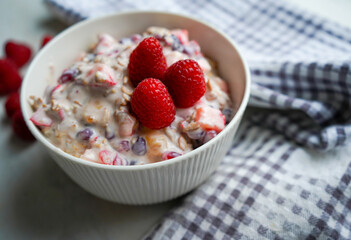 Bowl of homemade granola with yogurt and fresh berries on wooden background top view