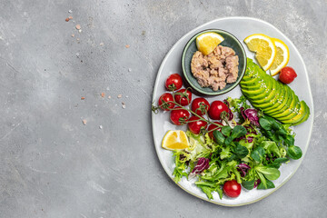 Ingredients for making Tuna fish salad on dark background. Lettuce, cherry tomatoes, avocado and red onions. Clean healthy detox eating. Vegan vegetarian food. Making healthy salad. top view