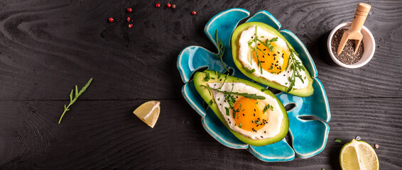 Fototapeta na wymiar Roasted avocado egg boats, fresh arugula, ground pepper, Low carb high fat breakfast. top view