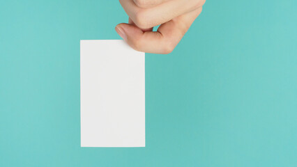 Empty space for text.Male hand holding white blank card isolated on mint green or Tiffany Blue background.