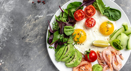 Ketogenic breakfast. Keto low carb salmon, boiled shrimps, prawns, fried eggs, fresh salad, tomatoes, cucumbers and avocado. top view. Low carb diet concept. high fat diet