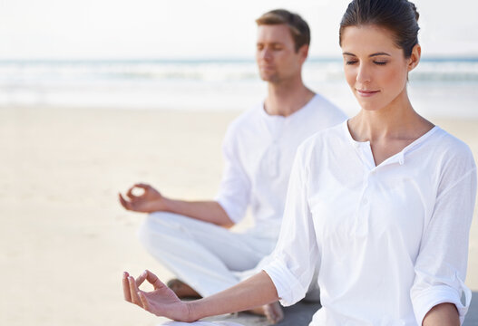 Seaside yoga. A young couple practising yoga on the beach.