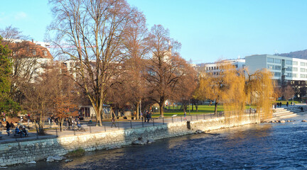 Zurich, Switzerland - December 18th 2021: People enjoying autumnal colours and sunlight in a park at the Limmat river