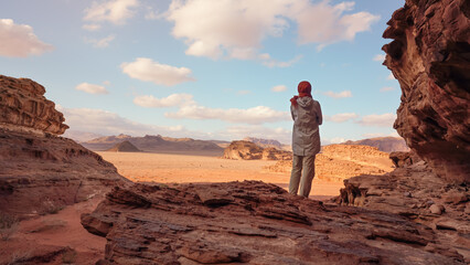 Young woman standing on rocky ground in desert landscape, view from behind. Wadi Rum, Jordan